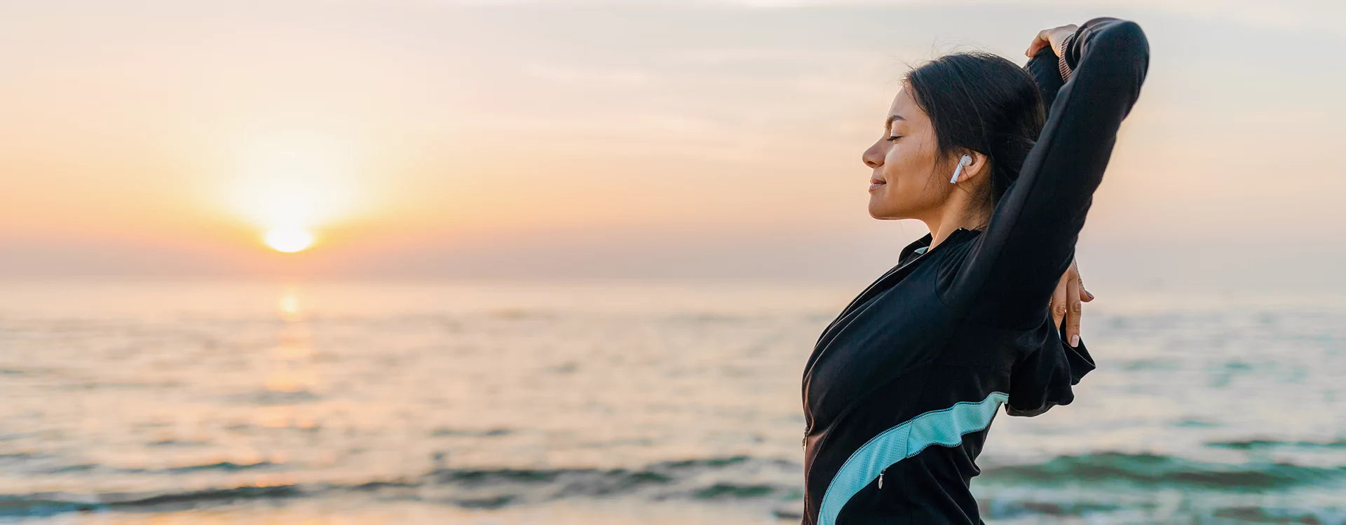 Woman stretching on a beach at sunset